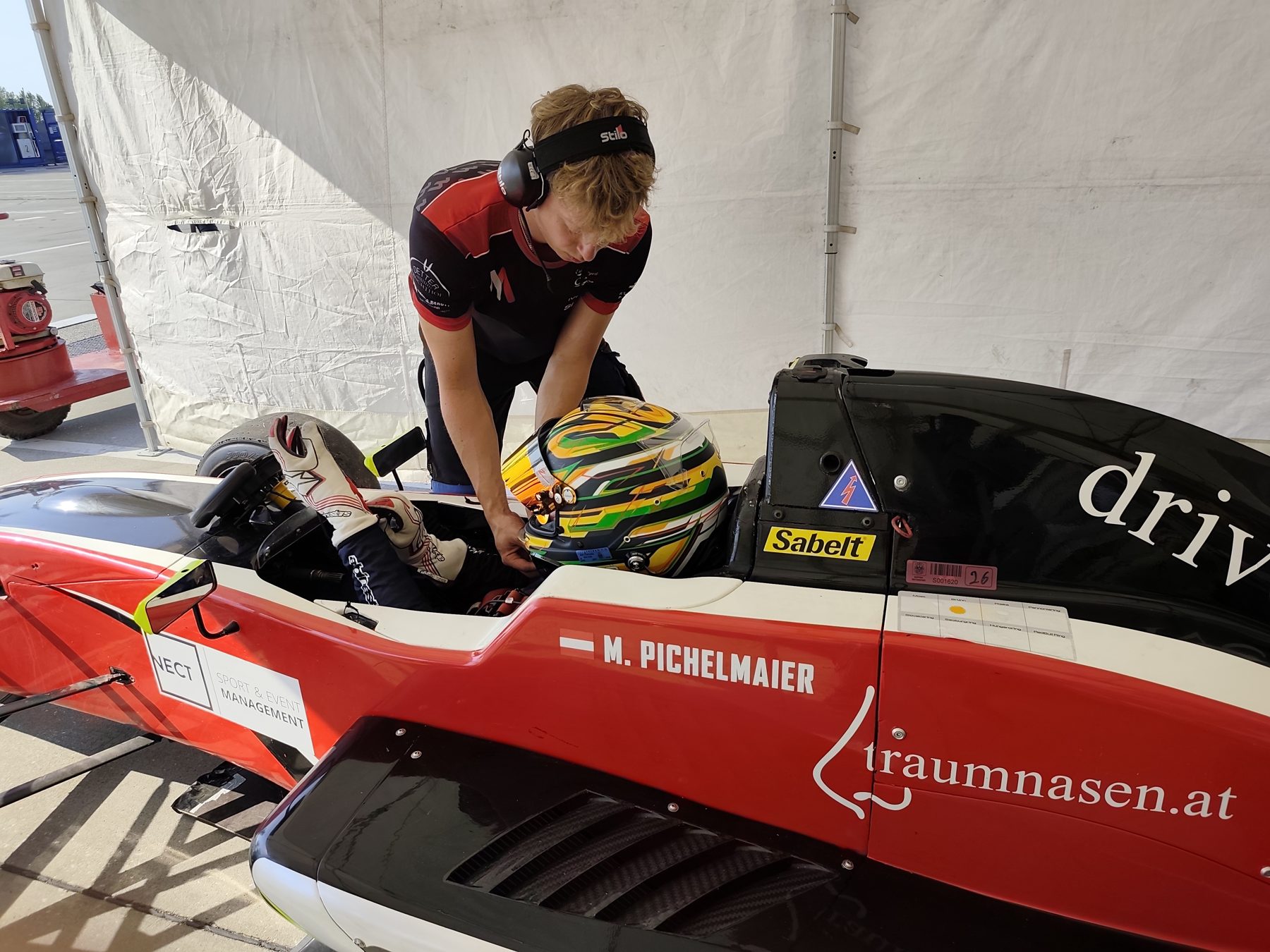 Mechaniker der Makolm-Crew hilft Michi Pichelmaier beim Anschnallen im Formel-Renault